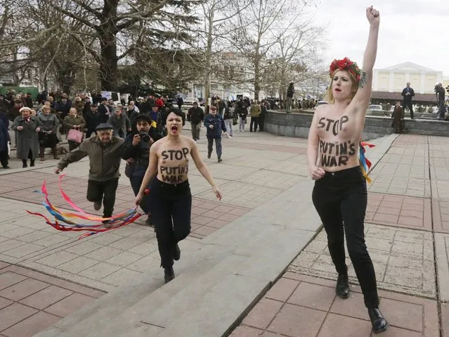 Pro-Russian protesters try to stop members of the feminist group Femen protest against Putin's policy concerning Ukraine during a pro-Russian rally near the Crimea's parliment in Simferopol. (Photo by Maxim Shipenkov/EPA)