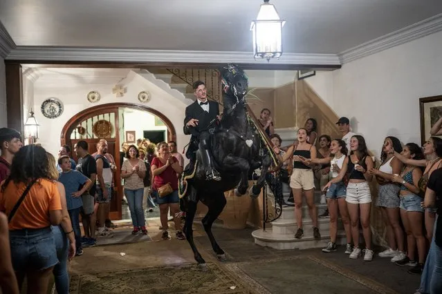 A horseman rides his horse inside a house during Sant Joan Festivity in downtown Ciutadella, Spain, in the early hours of Saturday, June 25, 2022. (Photo by Joan Mateu Parra/AP Photo)