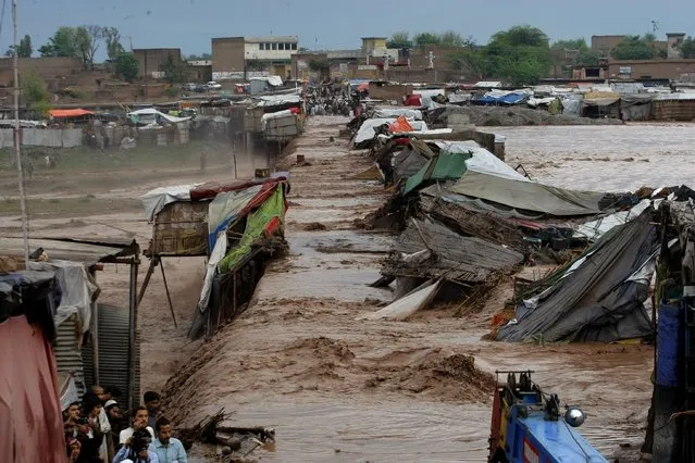 Pakistani villagers stand outside their homes during flash flooding on the outskirts of Peshawar, Pakistan, Sunday, April 3, 2016. A Pakistani national disaster management official says flash floods triggered by torrential rains have killed dozens of people in the country's northwest. (Photo by Mohammad Sajjad/AP Photo)