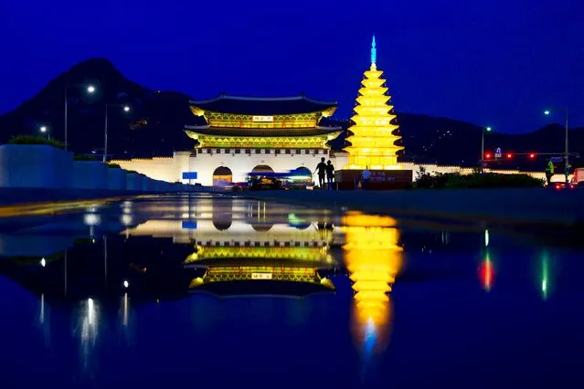 A couple walk past an illuminated pagoda as the gate of the Gyeongbokgung Palace is reflected in a gutter in Seoul, May 7, 2015. (Photo by Thomas Peter/Reuters)