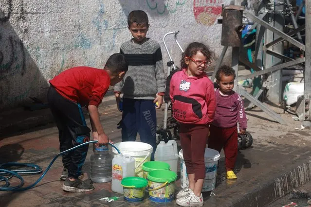 Palestinian children fetch water in Rafah in the southern Gaza Strip on March 30, 2024, amid the ongoing conflict between Israel and the militant group Hamas. (Photo by Mohammed Abed/AFP Photo)