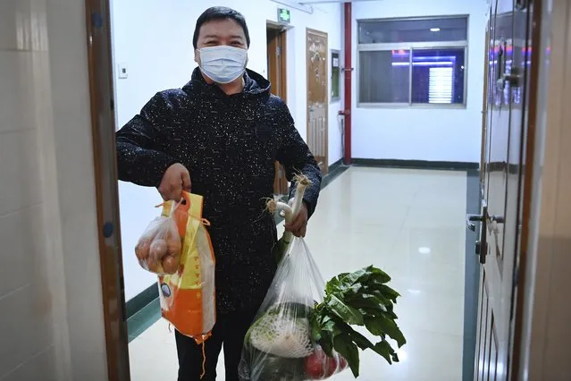 In this photo released by Xinhua News Agency, a community worker holds up daily necessities delivered to a household under closed-off management in Xi'an, capital of northwest China's Shaanxi Province, December 29, 2021. Chinese officials promised steady deliveries of groceries to residents of Xi'an, an ancient capital with 13 million people, that is currently under the strictest lockdown of a major Chinese city since Wuhan was shut early last year at the start of the pandemic. (Photo by Tao Ming/Xinhua via AP Photo)