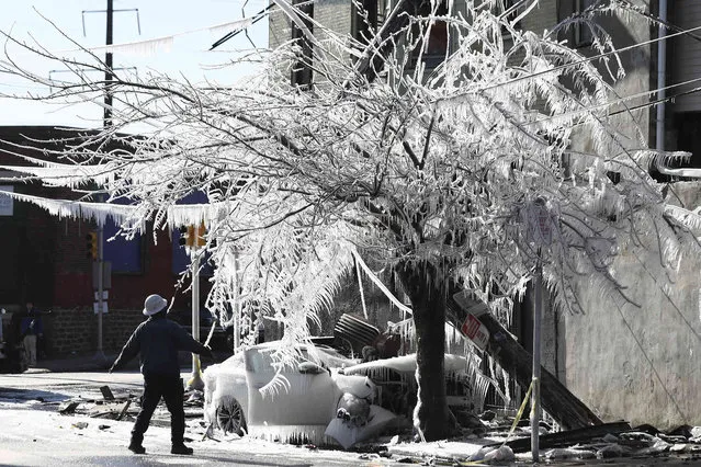 A crew member assess the damage of an accident as icicles form over a crashed car and tree at the corner of North 22nd Street and West Sedgley Avenue in Philadlephia on Tuesday, January 11, 2022. The crashed car reportedly caused a fire, along with a downed pole resulting in residents losing power. A winter weather advisory is currently in affect for the region, with the coldest temps being recorded since 2019. (Photo by Heather Khalifa/The Philadelphia Inquirer via AP Photo)