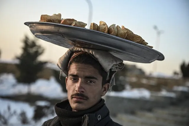A man carries samosa for sale on his head at the Wazir Akbar Khan hill on January 11, 2022. (Photo by Mohd Rasfan/AFP Photo)