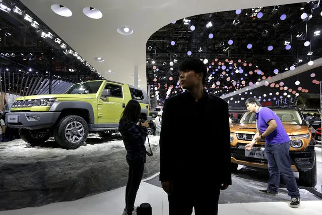 A security stands watch as journalists film the Chinese automaker BAIC Jeep model on display at the Beijing International Automotive Exhibition in Beijing, Monday, April 25, 2016. Automakers showcased a new generation of luxurious SUVs at China's biggest auto show of the year to lure buyers in its cooling, crowded market. (Photo by Andy Wong/AP Photo)