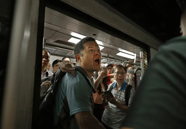 A passenger reacts after protesters blocked the train doors stopping the trains leaving at a subway platform in Hong Kong Wednesday, July 24, 2019. Subway train service was disrupted during morning rush hour after dozens of protesters staged what they called a disobedience movement to protest over a Sunday mob attack at a subway station. (Photo by Vincent Yu/AP Photo)