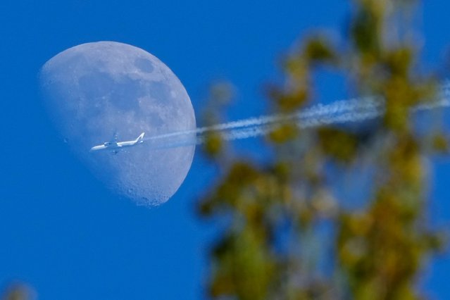 A Boeing 787-9 Dreamliner jet belonging to Air China flying from Madrid to Beijing passes the moon over the village of Podolye, 70 kilometres (43 miles) east of St. Petersburg, Russia, Friday, May 17, 2024. (Photo by Dmitri Lovetsky/AP Photo)