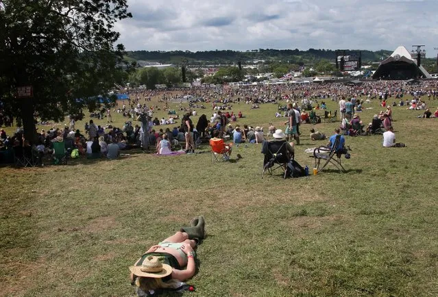A festival goer lies in the sunshine in front of the Pyramid Stage during Glastonbury Music Festival on Saturday, June 27, 2015 at Worthy Farm, Glastonbury, England. (Photo by Joel Ryan/Invision/AP Photo)