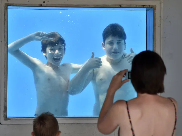 Julian, left, is photographed by his mother with friend Gianluca, right, under water at a public pool in Gelsenkirchen, Germany, on a hot Friday, July 3, 2015. Germany faces a heat wave with temperatures up to 38 degrees Celsius  (100 degrees Fahrenheit) at the weekend. (Photo by Martin Meissner/AP Photo)