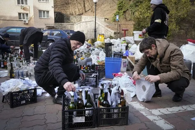 Members of civil defense prepare Molotov cocktails in a yard in Kyiv, Ukraine, Sunday, February 27, 2022. A Ukrainian official says street fighting has broken out in Ukraine's second-largest city of Kharkiv. Russian troops also put increasing pressure on strategic ports in the country's south following a wave of attacks on airfields and fuel facilities elsewhere that appeared to mark a new phase of Russia's invasion. (Photo by Efrem Lukatsky/AP Photo)
