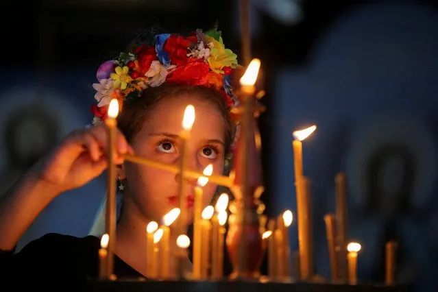 A girl descendant of Ukrainian immigrants lights candles during a mass at a Ukrainian Orthodox church, after the Russian invasion of Ukraine, in Canoas, Rio Grande do Sul state, Brazil on March 3, 2022. (Photo by Diego Vara/Reuters)