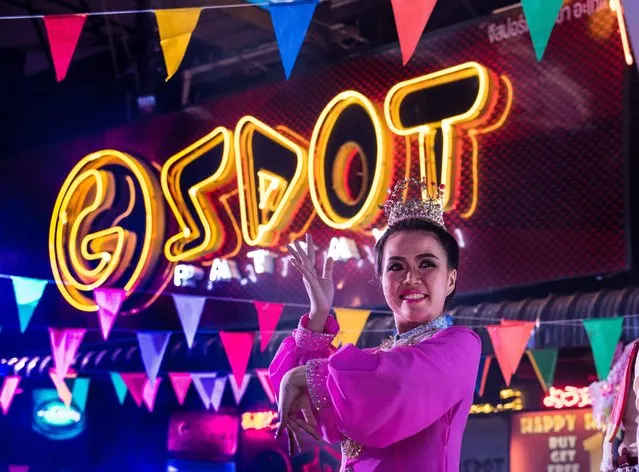 This photo taken on March 29, 2017 shows a performer dancing next to a neon sign from a go go bar in a red light district in Pattaya at an event used to highlight a push by the city to promote safety in the area. Two hours east of Bangkok, Pattaya' s bawdy reputation hails from the Vietnam War era when US GIs partied in their downtime. (Photo by Roberto Schmidt/AFP Photo)