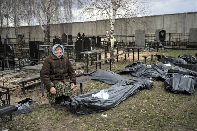 Nadiya Trubchaninova, 70, sits next to a plastic bag that contains the body of her son Vadym Trubchaninov, 48, who was killed by Russian soldiers in Bucha on March 30, in the outskirts of Kyiv, Ukraine, Tuesday, April 12, 2022. (Photo by Rodrigo Abd/AP Photo)