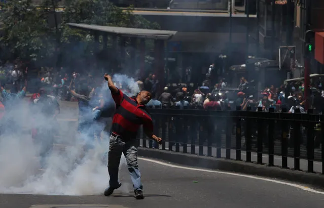 A man throws tear gas back at Bolivarian National Police as clashes break out during a protest demanding food, a few blocks from Miraflores presidential palace in Caracas, Venezuela, Thursday, June 2, 2016. (Photo by Fernando Llano/AP Photo)