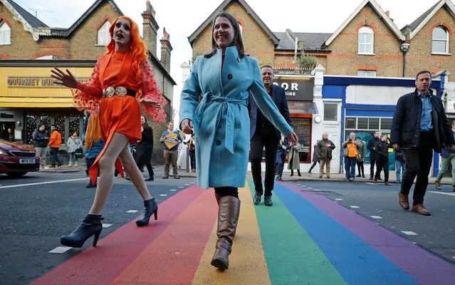 British opposition Liberal Democrats Party Leader Jo Swinson walks over a pedestrian crossing with a member of the LGBTQ community in Wimbledon, London, England, Wednesday, December 11, 2019 during the General Election campaign tour. Britain goes to the polls on Dec. 12. (Photo by Frank Augstein/AP Photo)
