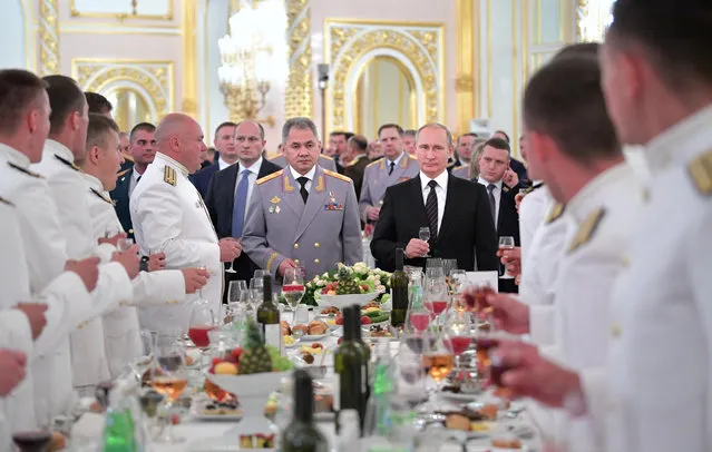 Russian President Vladimir Putin, center right, and Defence Minister Sergei Shoigu, center left, toast in the Kremlin during a meeting with graduates of military and police academies in Moscow, Russia, Wednesday, June 28, 2017. Putin has pledged to continue efforts to beef up the Russian military and law-enforcement agencies. (Photo by Alexei Druzhinin/Sputnik/Kremlin Pool Photo via AP Photo)