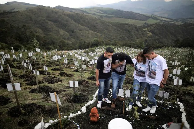 Relatives of Luis Enrique Rodriguez, who died of COVID-19, visit where he was buried on a hill at the El Pajonal de Cogua Natural Reserve, in Cogua, north of Bogota, Colombia, Monday, October 25, 2021. Rodriguez died May 14, 2021. Relatives bury the ashes of their loved ones who died of coronavirus and plant a tree in their memory. (Photo by Ivan Valencia/AP Photo)