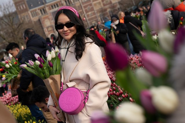 A woman poses for a picture as thousands of people picked free tulips on national tulip day which marked the opening of the 2024 tulip season on Museum Square in Amsterdam, Netherlands, Saturday, January 20, 2024. (Photo by Peter Dejong/AP Photo)