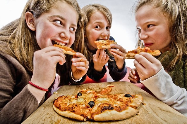 3 teenagers eating pizza in Brussels. (Photo by Carol Kohen/Getty Images)