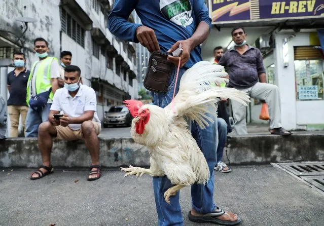 A man holds a chicken bought from a seller in Kuala Lumpur, Malaysia on May 25, 2022. (Photo by Hasnoor Hussain/Reuters)
