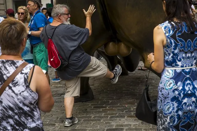 Tourists pose for photographs with a landmark statue of a bull in New York August 24, 2015. (Photo by Lucas Jackson/Reuters)