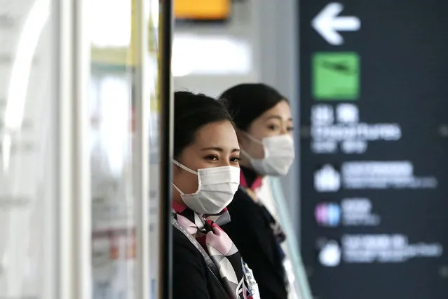Airlines ground crews with protective masks to protect against the coronavirus stand at a check-in counter at the Haneda International Airport in Tokyo Wednesday, March 18, 2020. For most people, the new coronavirus causes only mild or moderate symptoms. For some it can cause more severe illness, especially in older adults and people with existing health problems. (Photo by Eugene Hoshiko/AP Photo)