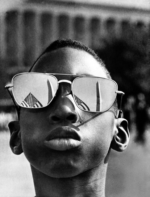 The top of the Washington Monument and part of a U.S. flag are reflected in the sunglasses of Austin Clinton Brown, 9, of Gainesville, Ga., as he poses at the Capitol where he joins others in the March on Washington, August 28, 1963. (Photo by AP Photo)