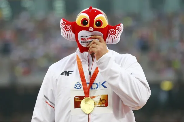 Piotr Malachowski of Poland, gold medal, hides his face with the official mascot as he poses on the podium after the men's discus throw event during the 15th IAAF World Championships at the National Stadium in Beijing, China, August 30, 2015. (Photo by Damir Sagolj/Reuters)