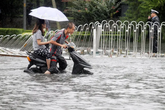 People ride along a flooded street during a heavy rainfall in Beijing, China, July 20, 2016. Picture taken July 20, 2016. (Photo by Reuters/China Daily)