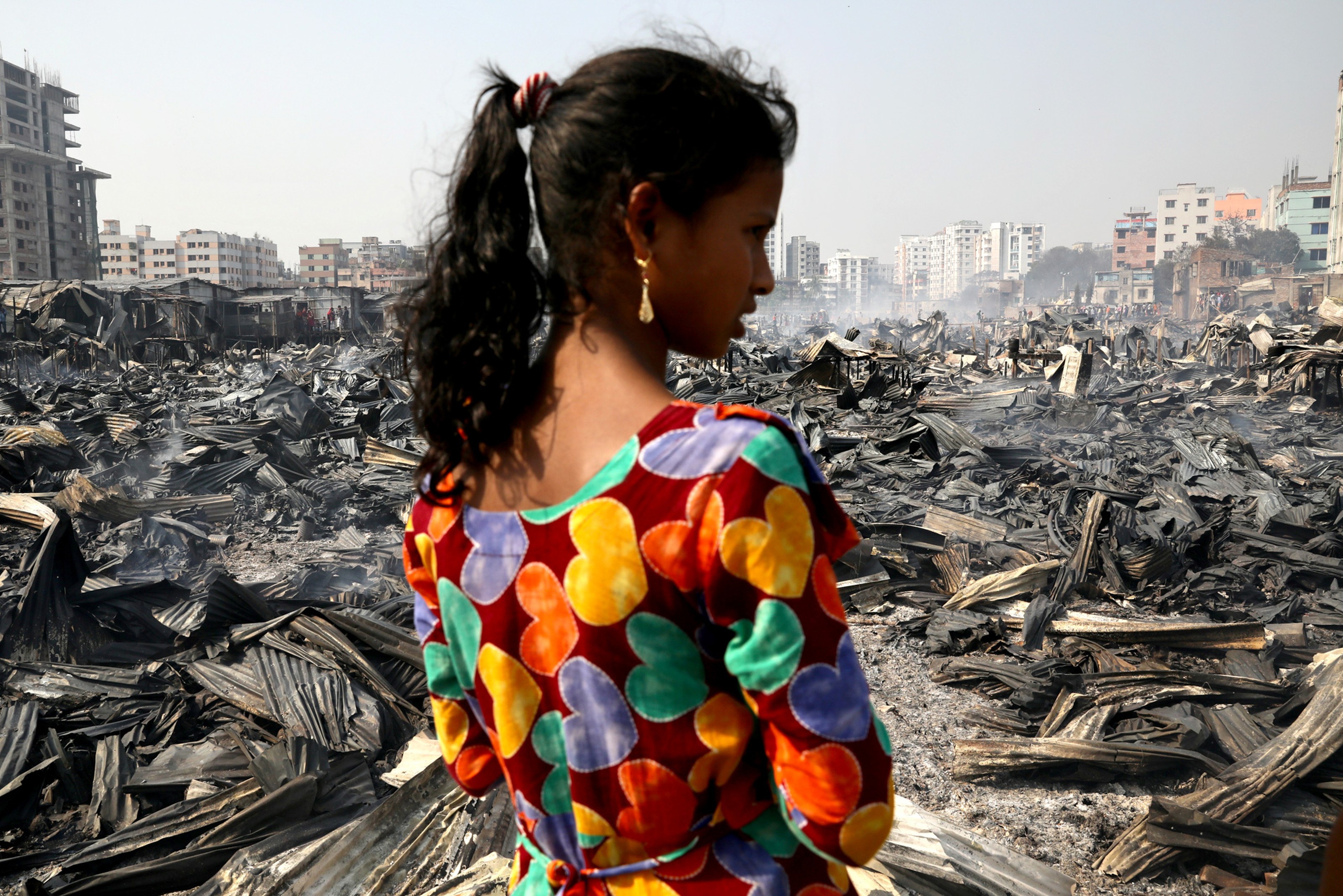 A girl looks on after a fire broke out in a slum in Dhaka, Bangladesh, Marc...