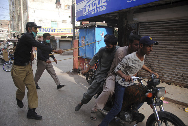 In this Monday, April 13, 2020 file photo, police officers try to restrict people from defying the nation-wide lockdown to curb the spread of the coronavirus, in Hyderabad, Pakistan. Wealthier Western countries are considering how to ease lockdown restrictions and start taking gradual steps toward reviving business and daily life. But many developing countries, particularly in the Middle East and Africa, can hardly afford the luxury of any misstep. (Photo by Pervez Masih/AP Photo/File)