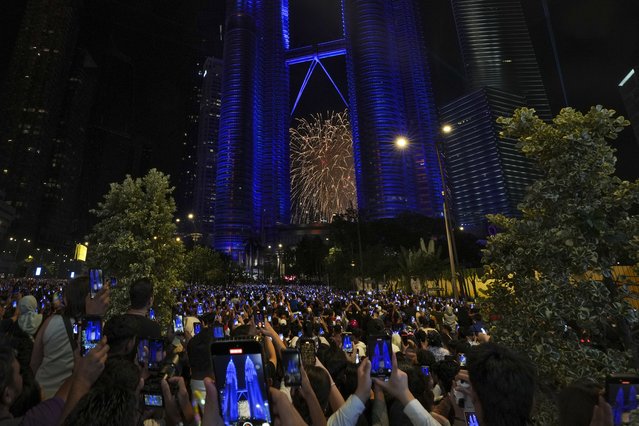 People take smartphones photos of the fireworks exploding near the Petronas Twin Towers, during the New Year's celebrations in Kuala Lumpur, Malaysia, Wednesday, January 1, 2025. (Photo by Andy Wong/AP Photo)