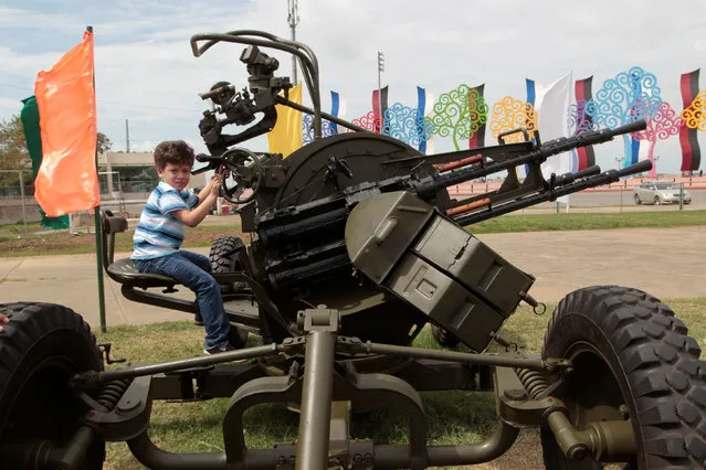 A child sits on an anti aircraft gun during the Static Military Civic Exhibition in Managua, Nicaragua August 17, 2016. (Photo by Oswaldo Rivas/Reuters)
