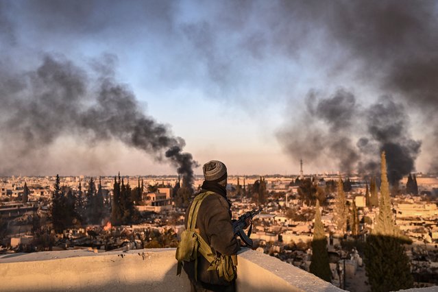A gunman stands on the roof of a building to push away looters from the Najha military housing complex in southeast Damascus on December 17, 2024. Islamist-led rebels took Damascus in a lightning offensive on December 8, ousting president Bashar al-Assad and ending five decades of Baath rule in Syria. (Photo by Aris Messinis/AFP Photo)