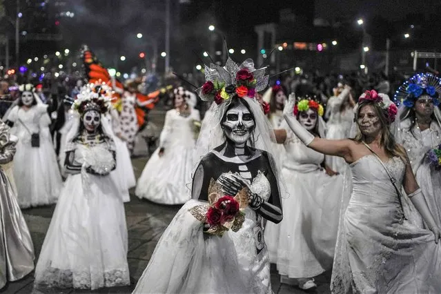 People dressed as Mexico's iconic “Catrinas” march in the Grand Procession of the Catrinas, part of upcoming Day of the Dead celebrations in Mexico City, Sunday, October 23, 2022. (Photo by Eduardo Verdugo/AP Photo)