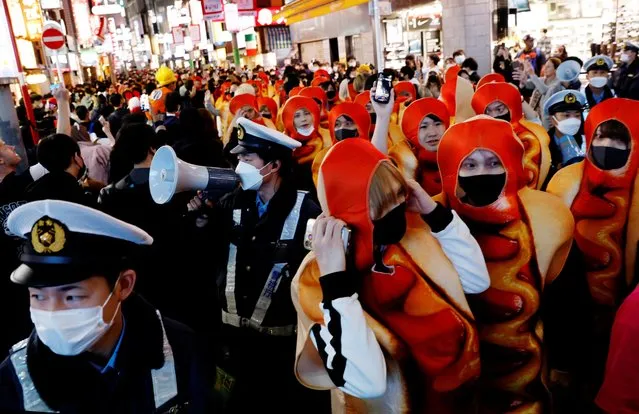 Police officers try to control crowds gathering to celebrate Halloween on the street at Tokyo's Shibuya entertainment and shopping district in Tokyo, Japan on October 31, 2022. (Photo by Kim Kyung-Hoon/Reuters)