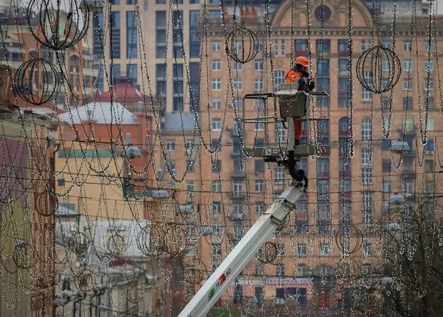 A worker installs decorative lights for the upcoming Christmas and New Year celebrations, as Russia's attack on Ukraine continues, in central Kyiv, Ukraine on November 15, 2022. (Photo by Gleb Garanich/Reuters)
