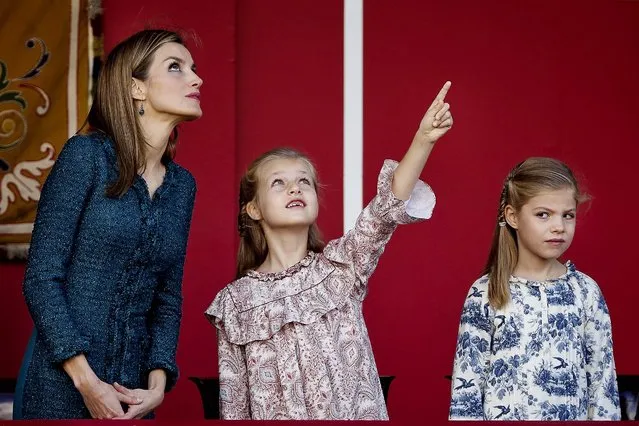 Spain's Crown Princess Leonor, talks with her mother Spain's Queen Letizia, left, in presence of Princess Sofia, right, while they attend a military parade during the holiday known as Dia de la Hispanidad, Spain's National Day,  in Madrid, Spain, Sunday, October 12, 2014. King Felipe VI presided the military parade as they celebrate the day Christopher Columbus discovered America in the name of the Spanish Crown. (Photo by Daniel Ochoa de Olza/AP Photo)