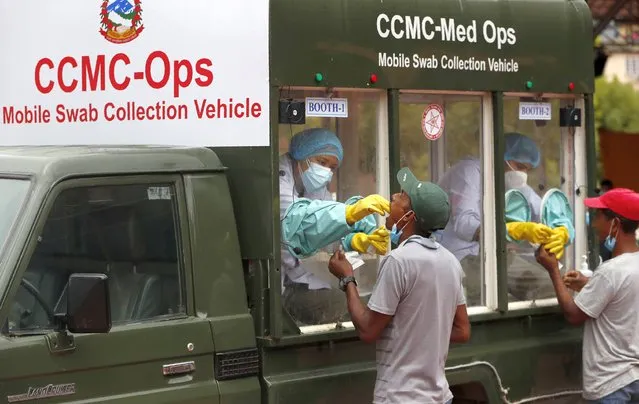 Health personnel in a mobile swab collection vehicle collect samples from Nepalese people who have travelled outside the Kathmandu valley for COVID-19 test in Kathmandu, Nepal, Thursday, July 30, 2020. (Photo by Niranjan Shrestha/AP Photo)