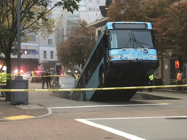 Authorities investigate after a Port Authority bus was caught in a sinkhole in downtown Pittsburgh on Monday, October 28, 2019. The Port Authority of Allegheny County says the lone passenger is being treated Monday morning for minor injuries. (Photo by Darrell Sapp/Pittsburgh Post-Gazette via AP Photo)