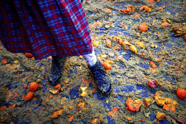 A reveller stands within smashed oranges as different teams take part in a fight with oranges during an annual carnival battle in Ivrea, Italy on February 11, 2024. (Photo by Guglielmo Mangiapane/Reuters)