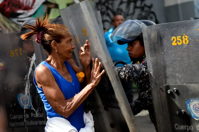 A woman confronts riot police during a protest against the shortage of food, amid Fuerzas Armadas avenue in Caracas on December 28, 2017. As Venezuelans protest in Caracas demanding the government's prommised pork – the main dish of the Christmas and New Year's dinner – President Nicolas Maduro attributes the shortage to international sabotage. (Photo by Federico Parra/AFP Photo)