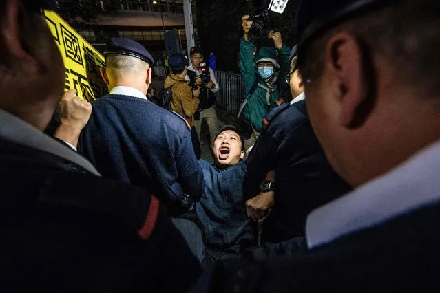 One of the last protestors is removed by members of security as he takes part in a New Year's Day pro-democracy rally in Hong Kong at the recently reopened Civic Square late on January 1, 2018. Angry protesters marched through Hong Kong on January 1 against what they described as suppression by Beijing, days after Chinese authorities ruled that part of a city rail station would come under mainland law. (Photo by Anthony Wallace/AFP Photo)