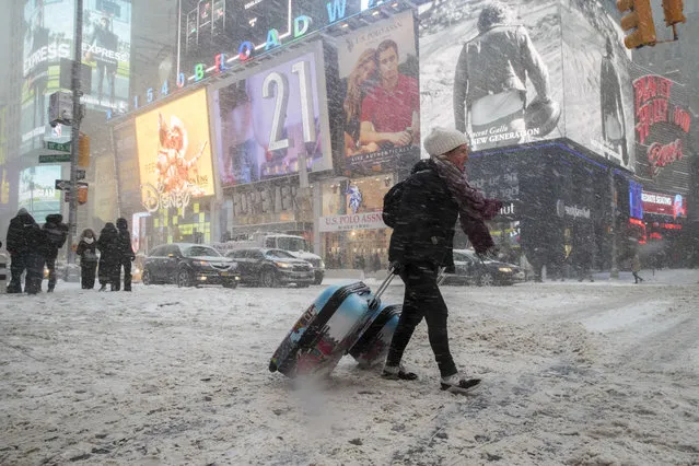 Rebecca Hollis of New Zealand drags her suitcases in a snowstorm through Times Square on her way to a hotel, Thursday, January 4, 2018, in New York. A massive winter storm swept from the Carolinas to Maine on Thursday, dumping snow along the coast and bringing strong winds that will usher in possible record-breaking cold. (Photo by Mary Altaffer/AP Photo)