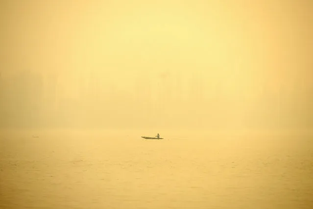 A man rows a boat in the waters of Dal Lake amid foggy morning in Srinagar on October 31, 2022. (Photo by Tauseef Mustafa/AFP Photo)