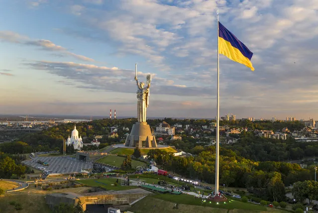 Ukraine's biggest flag flies some 90 metres above the city as it has been installed on the eve of the State Flag Day, with The Motherland Monument at centre, in Kyiv, Ukraine, Saturday, August 22, 2020. Ukraine marks the State Flag Day on August 23 and the Independence Day on Aug. 24. (Photo by Efrem Lukatsky/AP Photo)