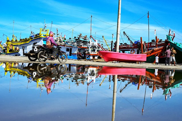 A man rides a rickshaw past fishing boats moored at a port in Banda Aceh, Indonesia on June 13, 2025. (Photo by Chaideer Mahyuddin/AFP Photo)