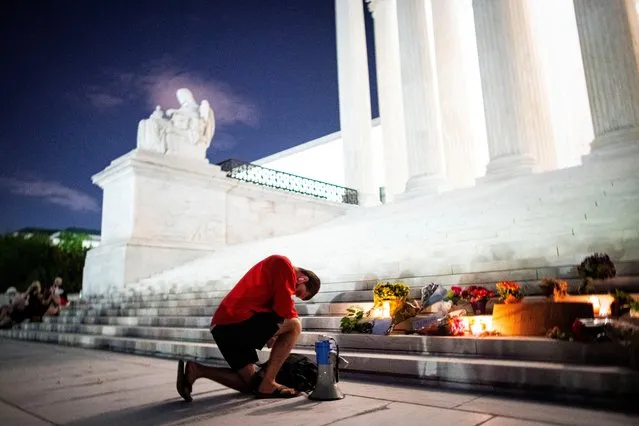 A man kneels as he brings a megaphone to a vigil on the steps of the U.S. Supreme Court following the death of U.S. Supreme Court Justice Ruth Bader Ginsburg, in Washington, U.S., September 18, 2020. (Photo by Al Drago/Reuters)