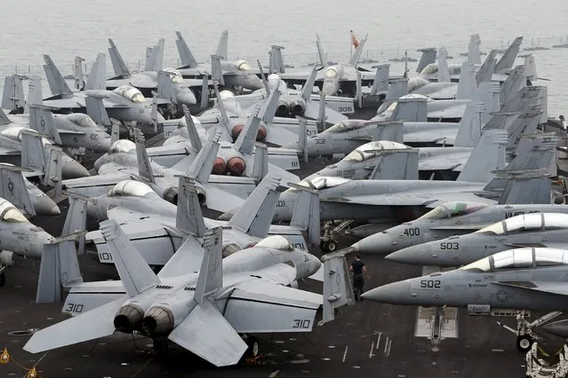 A U.S. Navy personnel walks among F/A 18 aircraft on the flight deck of the USS Theodore Roosevelt at Changi Navy Base in Singapore October 24, 2015. The aircraft carrier and its strike group of 7 ships and 80 aircraft docked in Singapore on Saturday after completing a deployment to the Arabian Gulf for the last 7 months. (Photo by Edgar Su/Reuters)