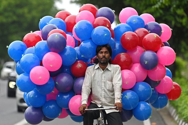 A vendor carrying plastic balls on a bicycle, rides along a street in New Delhi on July 17, 2025. (Photo by Arun Sankar/AFP Photo)